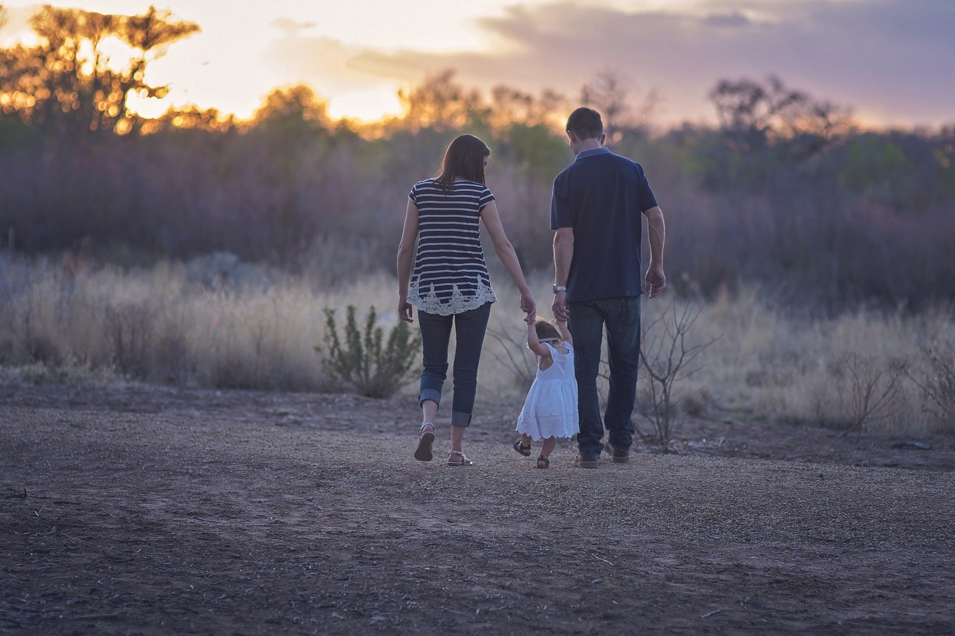 a couple walk holding a toddlers hands