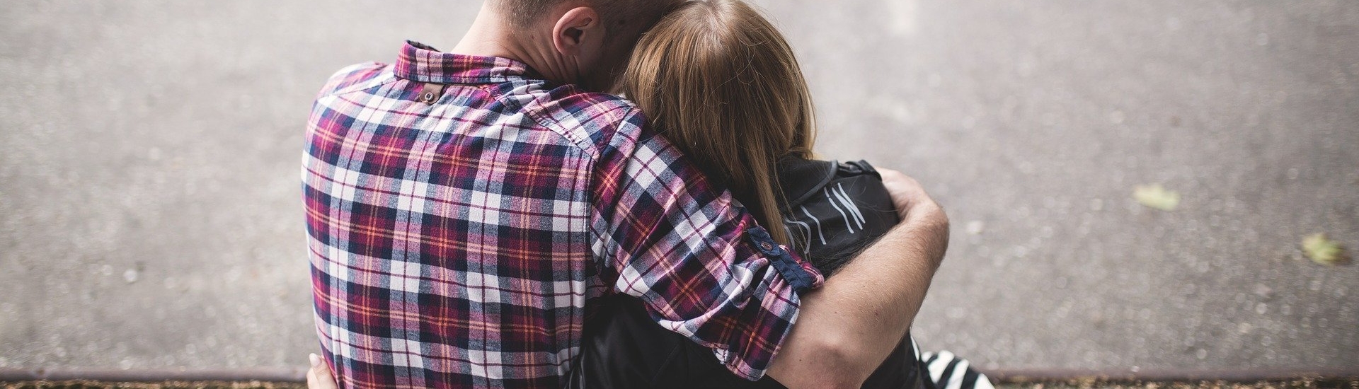 Young couple sit together with arms around each other